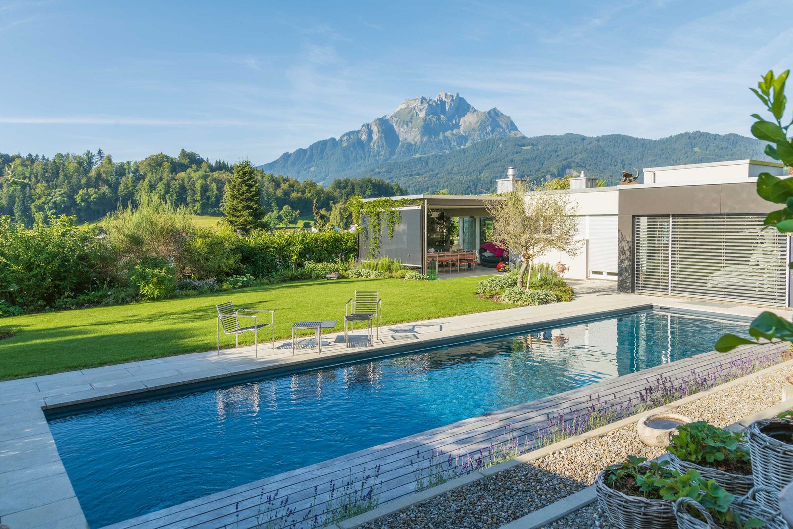 Grosser, aber dezenter Pool in dunklen Farben: Dieser Pool mit Turbinenschwimmanlage und grossartiger Sicht auf den Luzerner Hausberg fügt sich perfekt in den schönen Garten ein. Zireg Ziswiler GmbH, www.zireg.ch